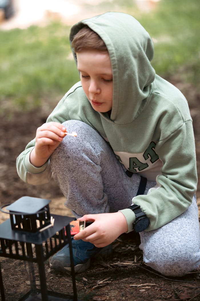 Young boy lighting a lantern outdoors in a forest. Peaceful and serene setting.